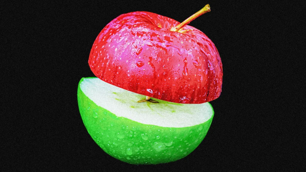 A digitally altered image of an apple split in half. The top half is red and the bottom half is green, both with water droplets. The apple appears to float against a black background.