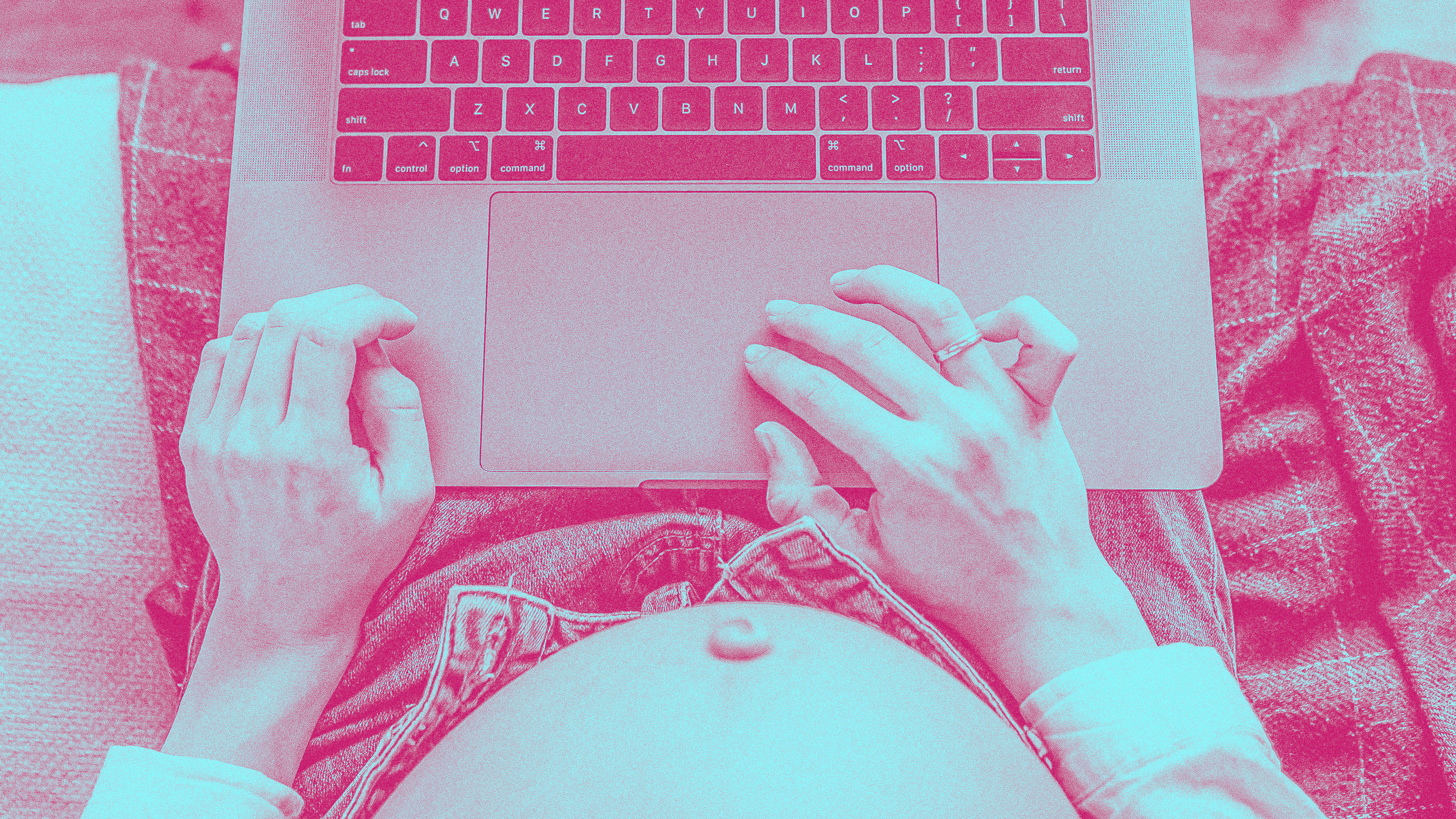 A person with a visible pregnant belly works on a laptop. The image is filtered in pink tones. One hand rests on the belly, while the other is on the laptop trackpad. The person is wearing a light-colored shirt and jeans.