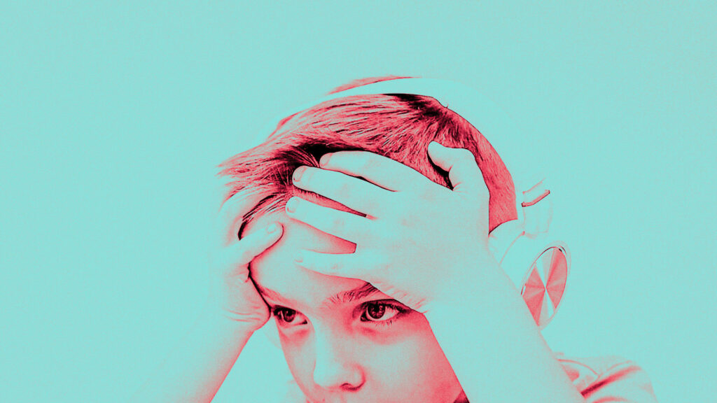 A young child wearing headphones looks intently ahead, with hands on top of their head, set against a light teal background. The image has a red color overlay.