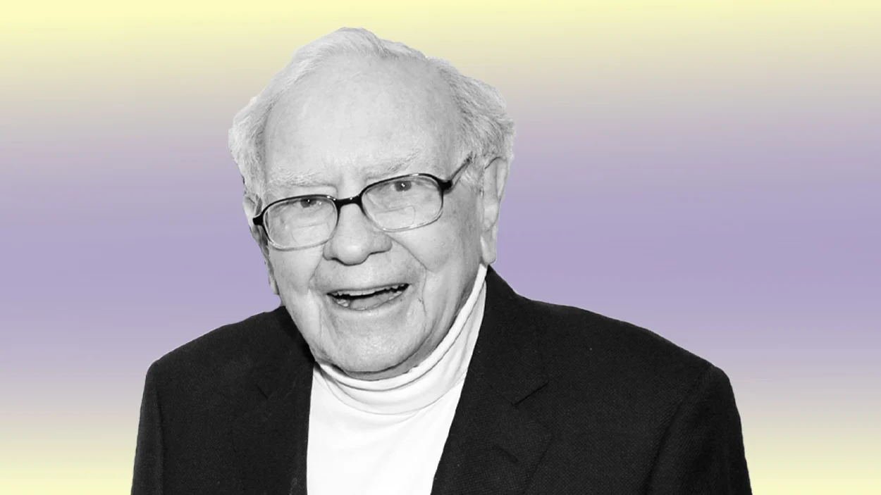 An elderly man with white hair and glasses smiles while wearing a dark blazer and a white turtleneck against a pastel yellow and purple gradient background.